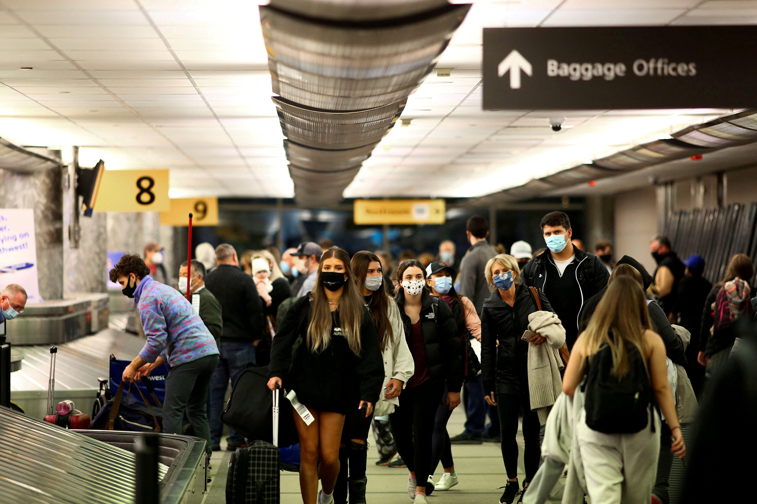 GY4UKRLCRNNA7FFAWDLHCJF3BY-scaled Travelers wearing protective face masks to prevent the spread of the coronavirus disease (COVID-19) reclaim their luggage at the airport in Denver, Colorado, U.S., November 24, 2020. REUTERS/Kevin Mohatt/File Photo